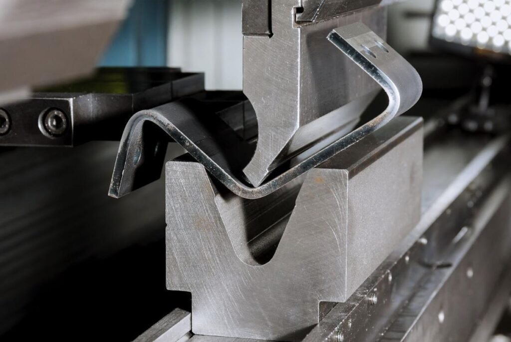 CNC press brake bending a sheet metal strip between a punch and die to form a precise angled profile.