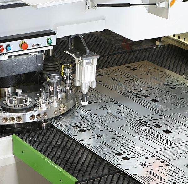 Industrial CNC laser cutting machine cutting openings into a large sheet metal panel in a sheet metal fabrication workshop.